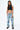 Pantalon Beleo Bleu Jean porté en pied par une mannequin femme, coupe droite, fleurs de lys noires, avec crop top noir