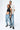Pantalon Beleo Bleu Jean porté en pied par un couple de mannequins, fleurs de lys noires et t-shirt écru Elevenparis