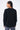 Pull Edmo Noir vu de dos sur mannequin femme, tresses collées, avec pantalon cargo gris