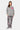 Pull col rond Edmo Gris porté en pied par une mannequin femme, cœur rose, pantalon gris à fleurs de lys roses