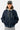 Blouson Eschott Bleu marine porté de face par un mannequin homme, casquette grise, capuche grise et bas côtelé
