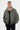 Blouson Eschott Kaki porté de face par un mannequin homme, capuche grise amovible, écusson cœur et pantalon noir