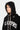 Accessoire Fanette Noir, cagoule noire à coutures écrues portée par une femme, sweat en maille à inscription Eleven Paris