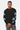 Sweat col rond Fifty Noir porté de face par un mannequin homme, lettrages bleu ciel sur les manches, jean gris