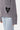 Cardigan Finlande Gris, zoom sur la poche ornée d'un cœur noir à croix et sur l'étiquette Eleven Paris de la manche