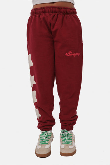 Jogging Fixion Bordeaux porté de face par une mannequin, logo rouge brodé sur la cuisse et étoiles blanches sur la jambe