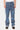 Pantalon Flex Bleu Jean porté de face par un mannequin homme, denim droit à fleurs de lys bleues et blanches, baskets noires