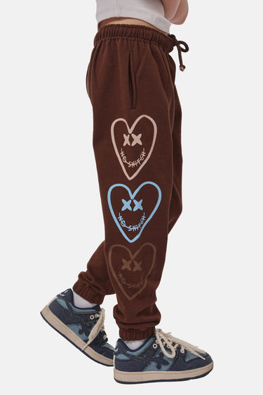 Jogging Fliora Marron porté de profil par un enfant, trois cœurs à croix brodés beige, bleu et marron sur la jambe