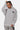Sweat à capuche Focaccia Gris Chiné porté par une femme, de face, petit coeur noir et texte violet sur la poitrine