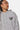 Sweat à capuche Focaccia Gris Chiné, gros plan de face sur le coeur brodé et le texte violet No Snitch Win Again