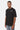 T-shirt Foufou Noir porté par un homme, de trois quarts, coeur blanc brodé et chaîne au cou