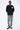 Pull col rond Edmo Noir porté en pied par un mannequin homme avec jean gris à croix et baskets noires