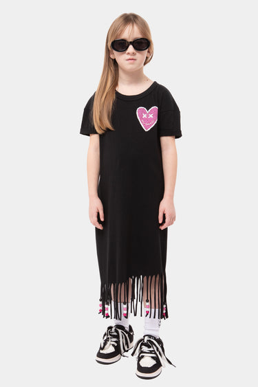 Robe enfant Jacky Noir à franges, portée en pied par une fille avec lunettes noires, cœur rose sur la poitrine