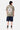 T-shirt Jamaica Kaki vu de dos en pied sur un mannequin homme, fleur beige souriante, short en jean foncé