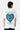 T-shirt Janiel Blanc vu de dos sur un mannequin homme, grand cœur zébré bleu et textes verts Made With Love