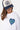 T-shirt Janiel Blanc en gros plan sur une mannequin femme avec casquette marine, cœur zébré bleu et vert
