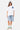 T-shirt Janiel Blanc porté de face en pied par une mannequin femme, petit cœur bleu, short en jean brodé et casquette