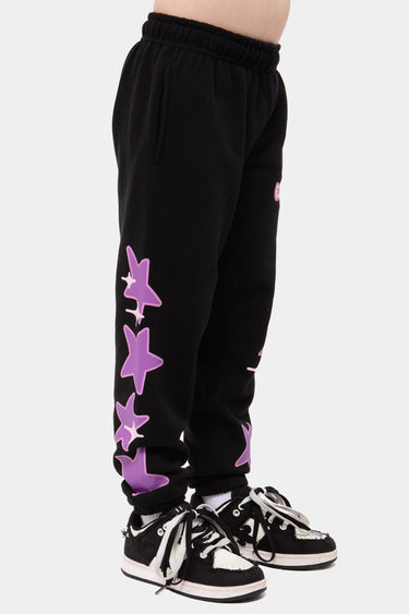 Jogging Jazzy Noir porté par un enfant, de profil, rangée d'étoiles violettes sur le côté de la jambe, baskets noires