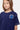 T-shirt Jea Bleu Marine porté par une fille, gros plan de face, surpiqûres blanches et petit lys bleu brodé