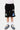 Short Jonah Noir en gros plan de face, taille élastiquée, écussons planète No Snitch, triangle bleu et logo blanc