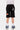 Short Jonah Noir en gros plan de dos, ourlet brut, écusson rouge Elvn et lettres NS blanches sur la jambe