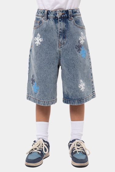 Short Jordan Bleu en jean délavé porté de face, ceinture à passants, fleurs de lys blanches, bleues et marine