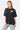 T-shirt June Noir Délavé oversize porté de face par une mannequin femme, petit logo vert sur la poitrine, jean à fleur de lys