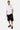 T-shirt Jwin Blanc porté en pied par un mannequin homme avec short noir, petit L'amour win sur la poitrine, baskets noires