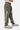 Jogging Foudre Kaki enfant porté de profil, éclair blanc et lettrage sur la jambe, petit motif fleur, baskets beige et vert