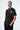 T-shirt Lys Noir delavé porté par un mannequin homme, main dans la poche du pantalon noir, inscription sur la poitrine