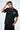 T-shirt Lys Noir delavé porté par un mannequin homme, pose la main sur la tête, chaîne et inscription blanche sur la poitrine