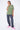 T-shirt Lys Kaki délavé porté par une mannequin femme en pose de trois quarts, pantalon cargo gris et baskets roses