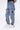 Jean Neleo Bleu jean porté par un enfant, détail des patchs fleur de lys noirs sur la jambe, baskets blanches