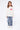 Jean Neleo Bleu jean porté par une fille avec pull blanc à coeur, de face en pied, patchs fleur de lys noirs