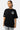 T-shirt Passau Noir porté par une mannequin femme, plan buste de face, emblème fleur de lys blanc et New York sur la manche