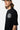T-shirt Passau Noir porté par un mannequin homme, vue de trois quarts et zoom sur l'emblème fleur de lys blanc de la poitrine