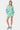 Chemise Penelope Vert à rayures blanches portée ouverte sur un short assorti, mannequin femme en pied, baskets bleues
