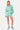 Short Jazeon Vert à rayures blanches porté avec la chemise assorti, mannequin femme de face en pied, baskets montantes bleues