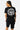 T-shirt court Plume Noir porté par une mannequin femme de dos, grand emblème fleur de lys blanc, short cargo noir