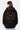 Sweat à capuche Poncho Noir porté par une mannequin femme de dos, smiley No Snitch et lettres gothiques motif léopard