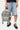Sac à dos July Kaki gris tenu à la main, lettrage Eleven peint sur la poche avant, petit cœur brodé et cordon coloré