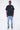 T-shirt Saule Noir Délavé porté en pied par un mannequin homme, de face, cœurs sur la poitrine, jean clair, baskets grises