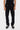 Pantalon cargo Suede Noir porté de face, poches à rabat à pressions et boutons-pressions aux chevilles, baskets noires