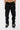 Pantalon cargo Suede Noir porté de face en plan resserré, deux poches à rabat à pressions, cordon et baskets noires