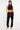 Pantalon cargo Suede blk noir porté en pied par une mannequin femme, casquette, haut court et baskets roses