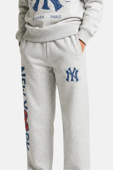 Jogging Tada Gris Chiné porté en plan resserré, logo NY bleu sur la cuisse et inscription New York sur la jambe