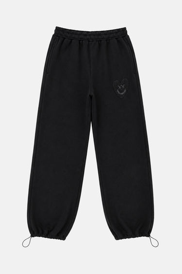 Jogging Tulum Noir de face à plat, cœur smiley noir sur noir sur la cuisse et cordons de serrage aux chevilles