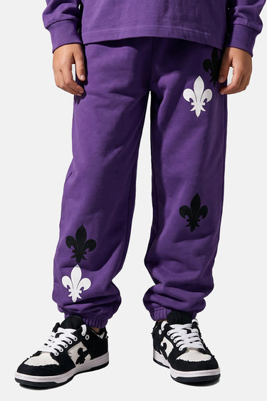 Jogging Tutti Violet porté de face en plan rapproché par un enfant, fleurs de lys noires et blanches et baskets