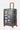 Valise Fugers Gris Foncé M de trois quarts, patchs colorés, poignée latérale argentée et roulettes orange
