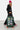 Valise Fugers Vert M tenue par une femme en bonnet rose et sweat noir, patchs colorés, roulettes orange